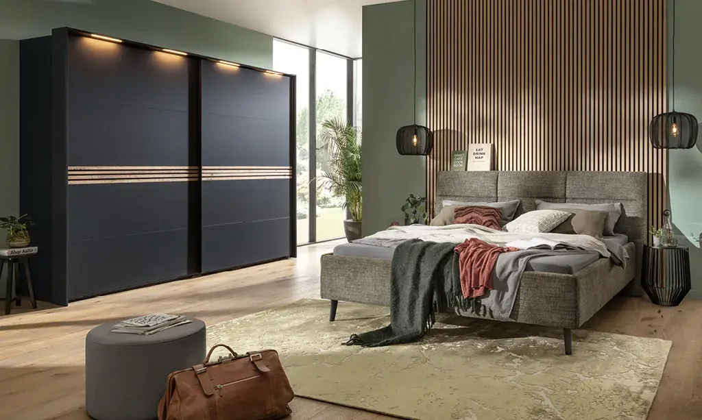 Modernes Schlafzimmer mit grauem Polsterbett und Schiebetürenschrank.